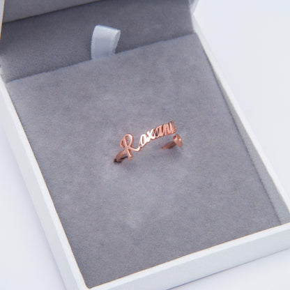 Person holding a gold Personalized Heart Name Ring, showcasing the adjustable band and comfortable fit. Perfect personalized gift. (Introduces a lifestyle element, emphasizes adjustability, and suggests gift-giving)