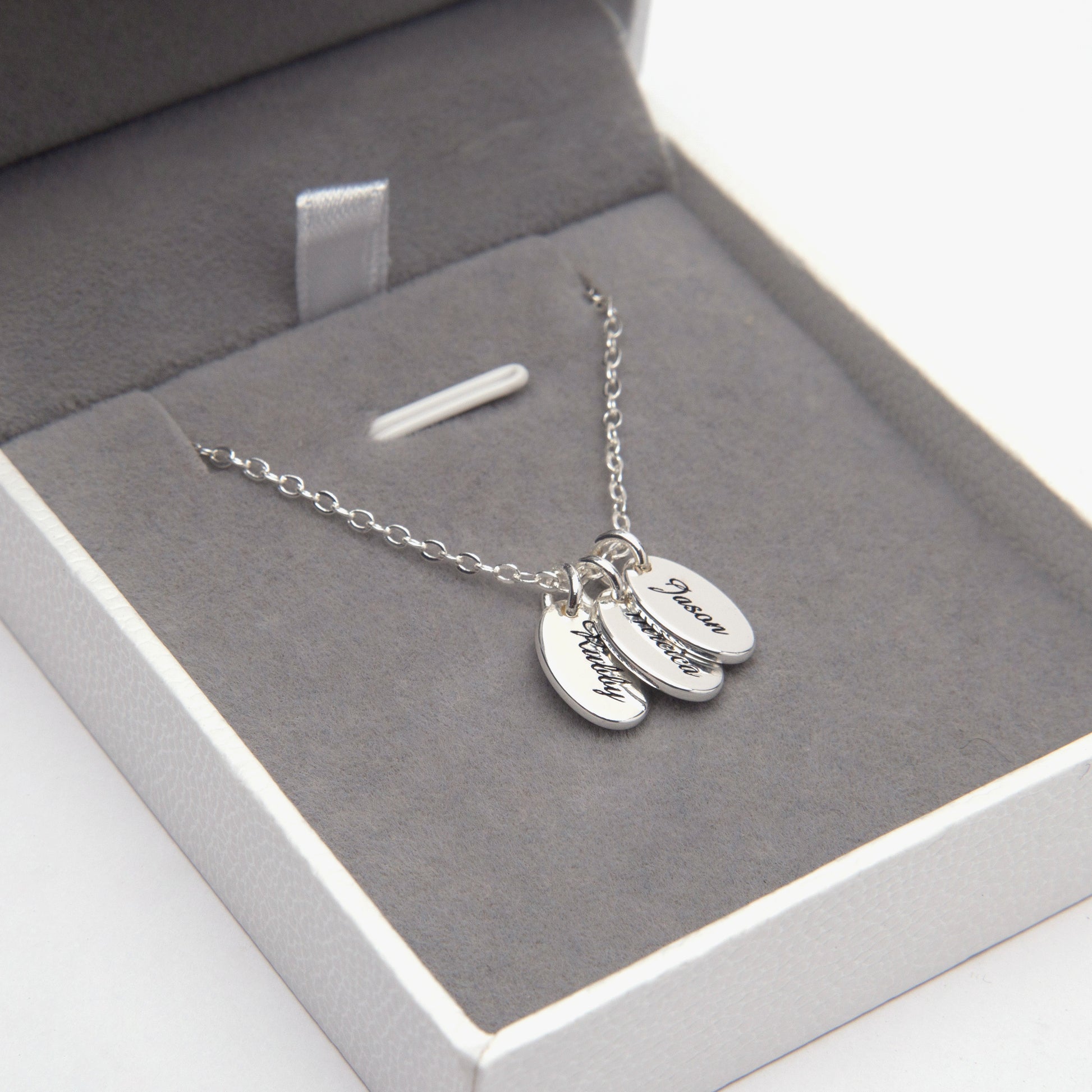 Close-up of a sterling silver dainty oval disc necklace nestled in a satin-lined gift box, showcasing its delicate craftsmanship. (Focuses on material and presentation, good for a close-up shot)