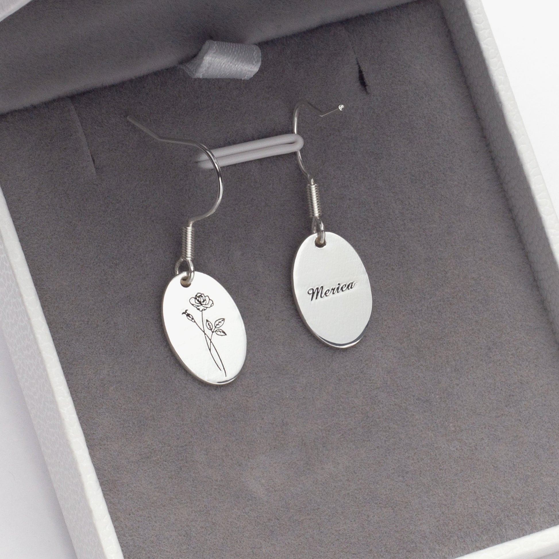 Close-up of sterling silver personalized rose earrings with "Emily" engraved, nestled in a gift box. (Focuses on metal type and personalization example, good for a close-up image)