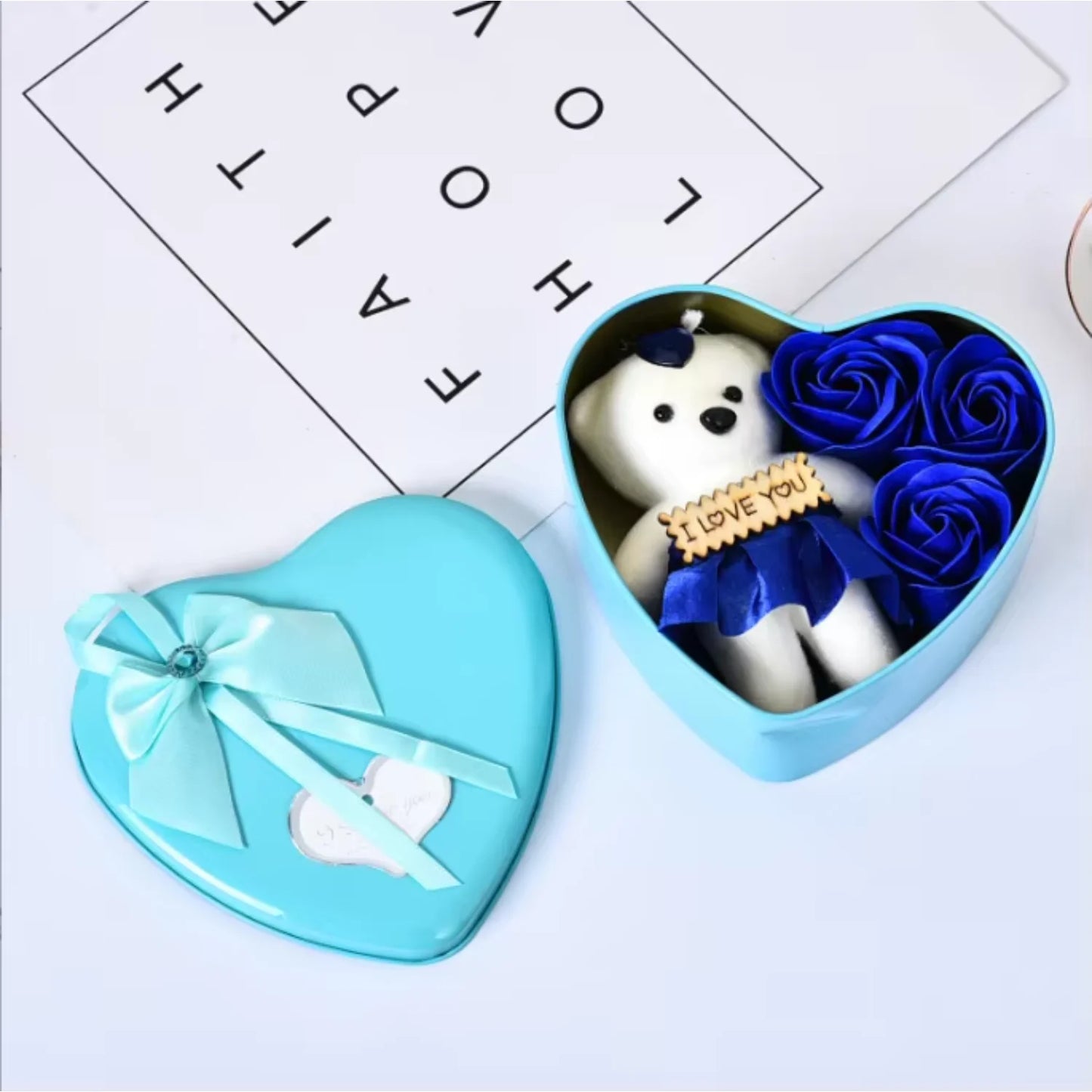 Teddy bear holding a heart, nestled in a heart-shaped gift box.