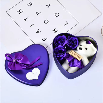 Red heart-shaped gift box with lid, containing soap roses and a plush bear.